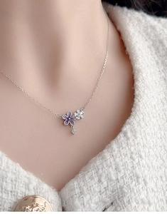 Close-up of a silver flower necklace with purple enamel and sparkling crystal details