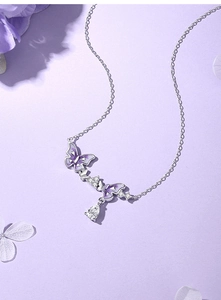 Detailed view of the purple butterfly pendant and pear-shaped crystal on a silver chain