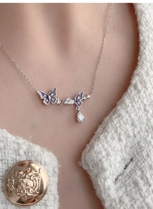 Close-up of 925 silver necklace with purple enamel butterflies and zircon teardrop pendant