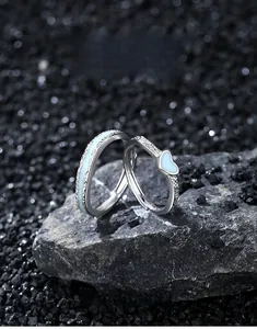 Vue macro des bagues de couple en argent S925 avec émail lumineux bleu sur roche noire