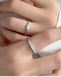 Gros plan des bagues de couple en argent S925 avec cœur bleu clair et texture martelée fine