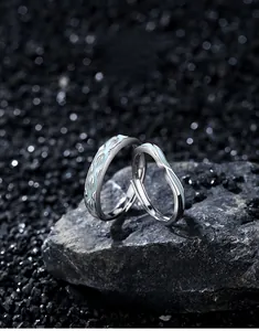 Macro shot of silver couple rings with blue enamel finish on dark textured stone
