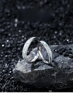 Detailed macro view of S925 sterling silver luminous galaxy rings on dark textured rocks