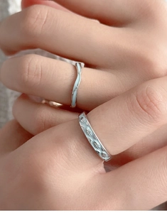 Detailed view of silver couple rings with light blue enamel and textured wave design