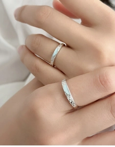 Close-up of 925 sterling silver couple rings with light blue enamel and hammered texture