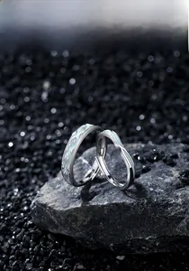 Detail of silver couple rings with swallow engraving on textured stone background