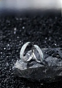 Macro view of S925 silver couple rings with blue fluid lava enamel on dark stone