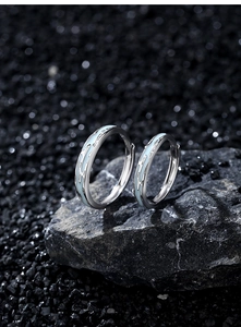 Macro detail of S925 silver couple rings with luminous blue enamel on dark rock