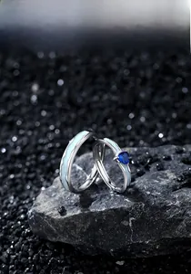 Detailed close-up of heart-shaped blue zircon and enamel waves on silver couple rings