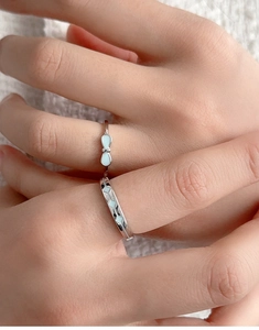 Detail of S925 silver luminous bow ring and geometric band on soft knit background