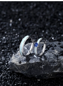 Macro shot of silver couples rings featuring blue wave enamel and a heart-shaped zircon