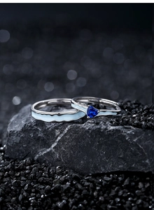 Macro detail of silver couple rings with blue heart zircon on dark textured stone