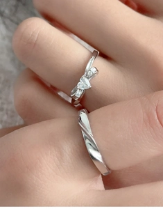 Detail von silbernen Paarringen mit Schleife, Herz-Zirkonia und gedrehtem Minimal-Band