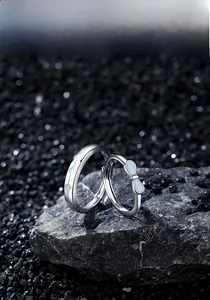 Detail of S925 sterling silver couple rings with blue enamel and bowknot on dark stone