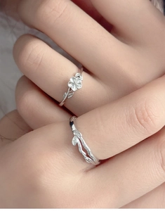 Detailed view of silver camellia flower and vine leaf rings on a model finger