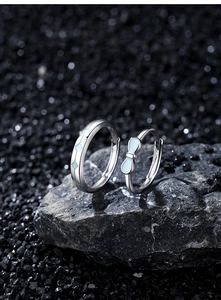 Macro shot of S925 sterling silver couple rings with luminous blue bow on dark stone