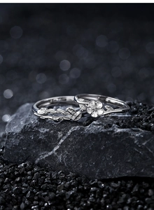 Macro shot of 925 silver camellia flower rings resting on dark natural stone background