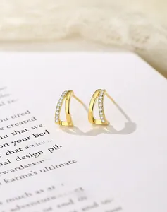 Detail of gold plated S925 silver stud earrings with parallel curves and cubic zirconia