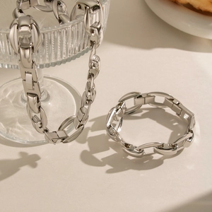 Chunky silver stainless steel chain link necklace and bracelet set displayed on glass