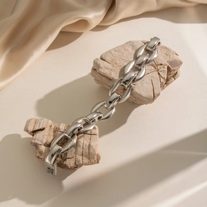 Macro shot of silver stainless steel thick link bracelet with folding clasp on satin