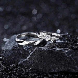 S925 Silber Paar Ringe mit herzförmigem Stein und gedrehtem Band auf dunklem Stein Hintergrund