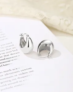 Macro detail of polished 925 sterling silver drop earrings on a vintage magazine background