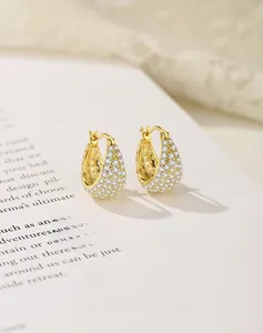 Macro shot of U-shaped gold plated silver earrings encrusted with rows of white zircons