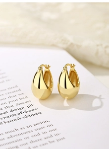 Close-up of golden teardrop earrings on vintage book page with elegant lace background
