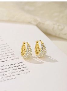 Close-up of S925 sterling silver handbag earrings with diamonds on a book page