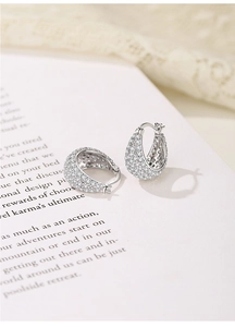 Close-up of S925 silver hoop earrings with full pavé cubic zirconia on magazine background