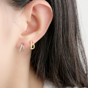 Minimalist double-layered silver and gold earrings with pavé zircons on female ear
