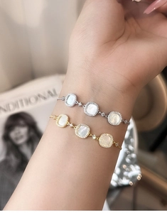 Detail of adjustable silver and gold bracelets with white shell and inlaid crystals