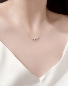 Detail of s925 silver smile necklace with sparkling pavé zircons worn on model neck