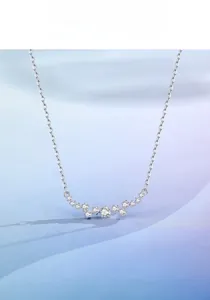 Close-up of S925 silver necklace with sparkling curved zircon pendant on silk background