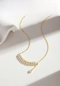 Macro detail of gold wheat ear necklace with rectangular zircon leaves and tassel pendant