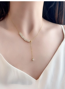 Close-up of golden wheat-shaped zircon necklace with tassel pendant on model
