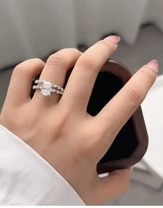 Detailed close-up of a double-row silver bridal ring set with an oval-cut diamond on hand
