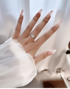 Detailed view of a heart-shaped moissanite ring with pave diamonds on a woman's finger