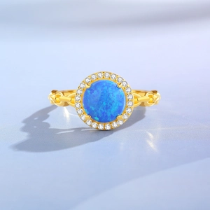 Golden 925 silver ring with round blue opal stone and halo of shimmering zircons