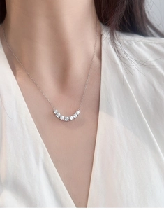 Close-up of elegant S925 silver necklace with seven-stone curved pendant on a female model