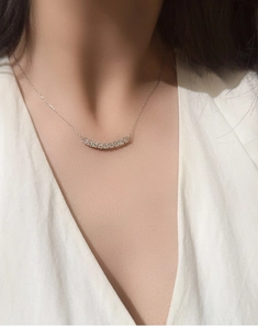 Close-up of S925 sterling silver necklace with D color moissanite curved pendant on a model