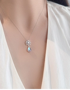 Detail of S925 silver daisy necklace with teardrop moonstone pendant on female model