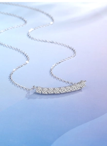 Macro shot of silver smile curved pendant with channel-set square moissanite stones