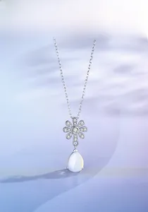 Macro detail of S925 silver daisy pendant with moonstone drop on blue fabric