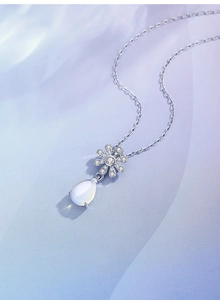Macro shot of S925 silver daisy pendant with teardrop moonstone on silk background