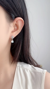 Detail of S925 silver daisy earring with a shimmering moonstone drop pendant on model