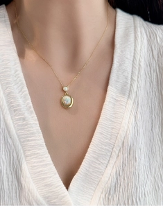 Détail d'un collier doré avec opale ovale blanche et zircon sur mannequin en col V