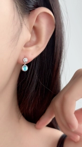Close-up of S925 silver stud earrings with moonstone and pavé crystals on ear