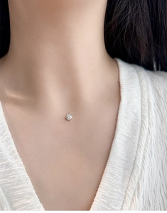 Close-up of 5mm round moissanite pendant on transparent invisible fishing line chain