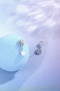 Detail view of daisy silver earrings with sparkling crystals and pear-shaped moonstone